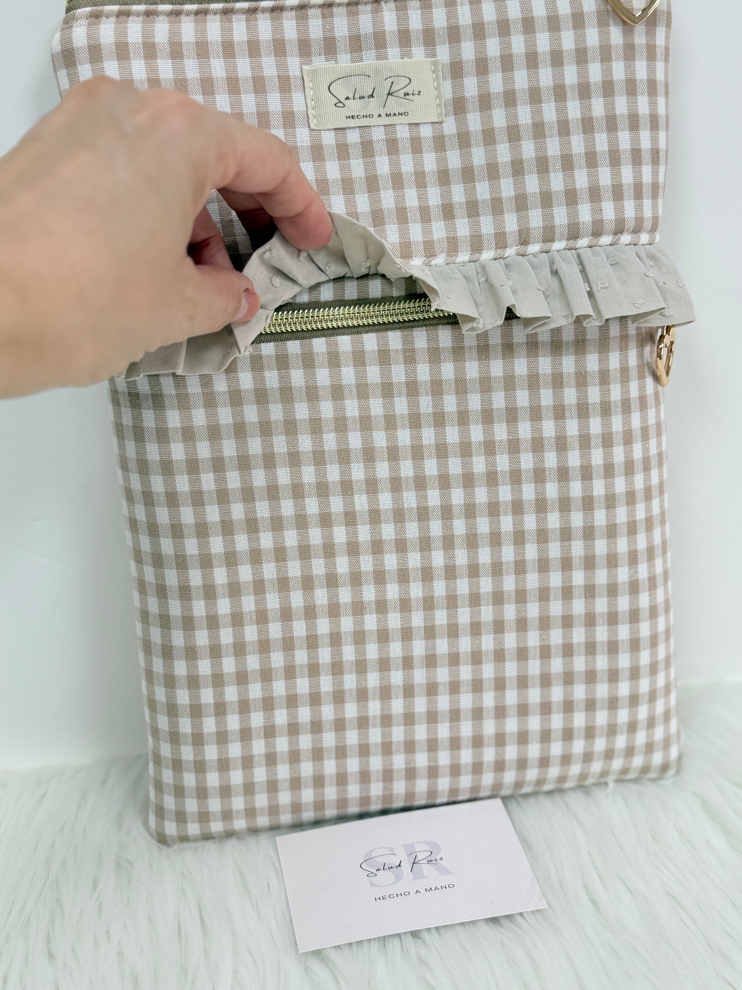 Detalle del bolsillo exterior con volante de una funda de tela acolchada hecha a mano para accesorios de lectura y tablets.