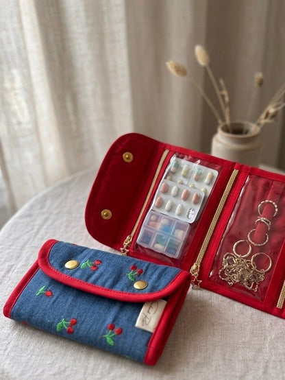 Organizador de joyas denim con bordado de cerezas abierto mostrando compartimentos.