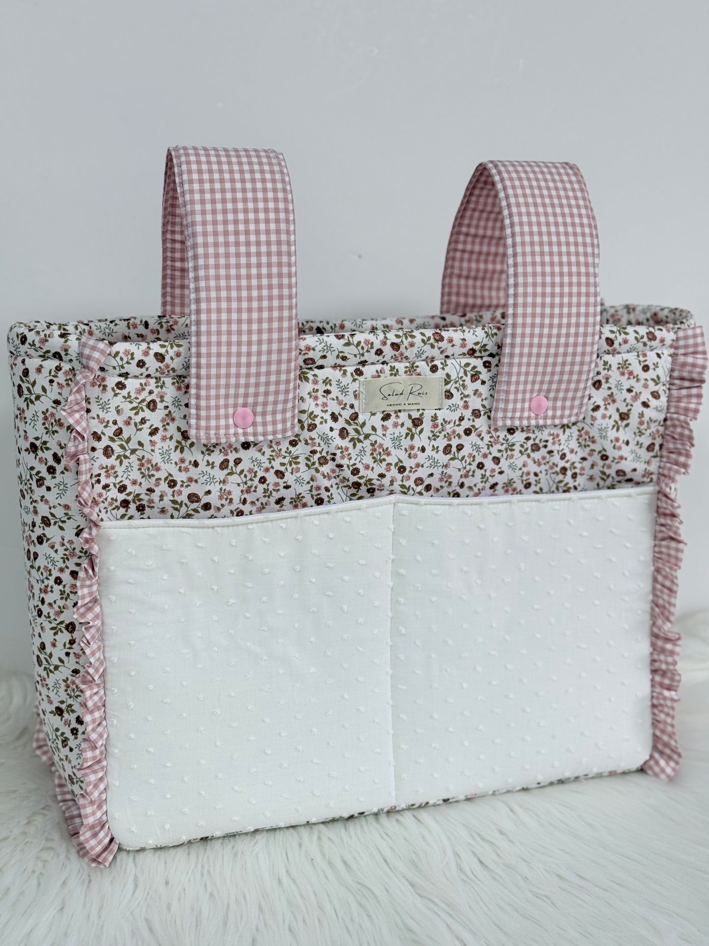 Bolso de tela floral con detalles vichy rosa colgado en carrito de bebé"