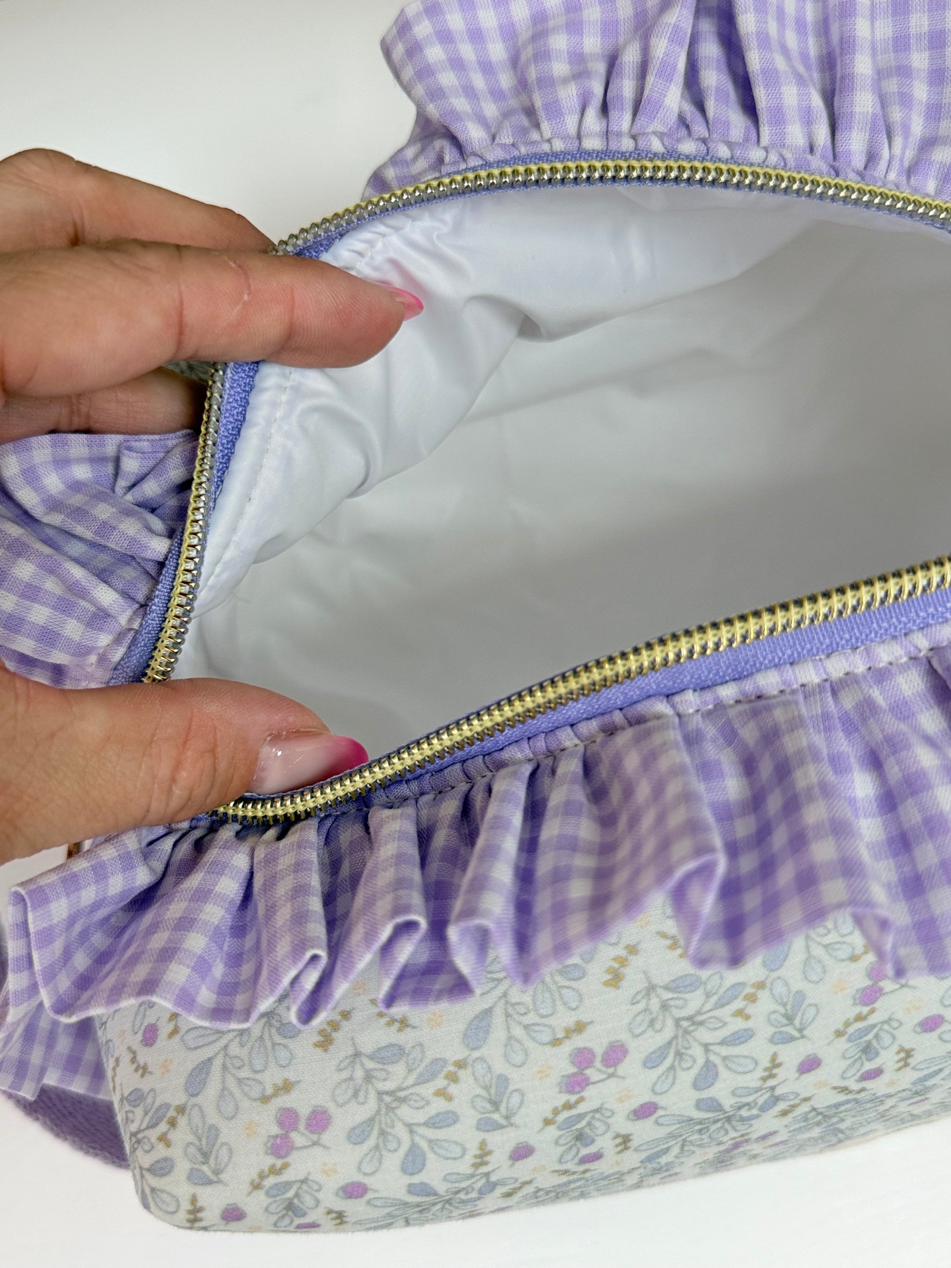 Interior de neceser cuadrado abierto con forro blanco impermeable y antimanchas mostrando espacio amplio con jabon y bote de cosmetico.