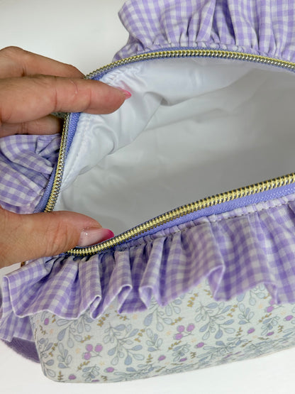 Interior de neceser cuadrado abierto con forro blanco impermeable y antimanchas mostrando espacio amplio con jabon y bote de cosmetico.