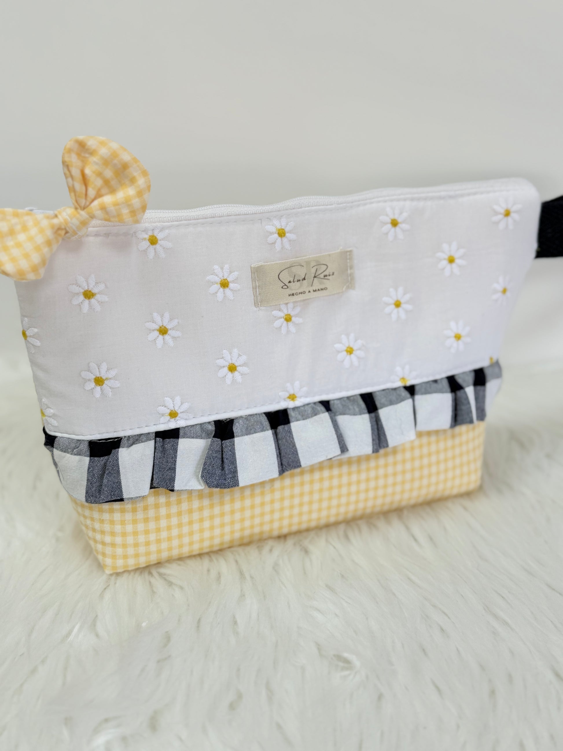 Neceser de tela artesanal de la colección margarita con volante vichy marino y lazo en la cremallera se puede usar como cartera de mano.