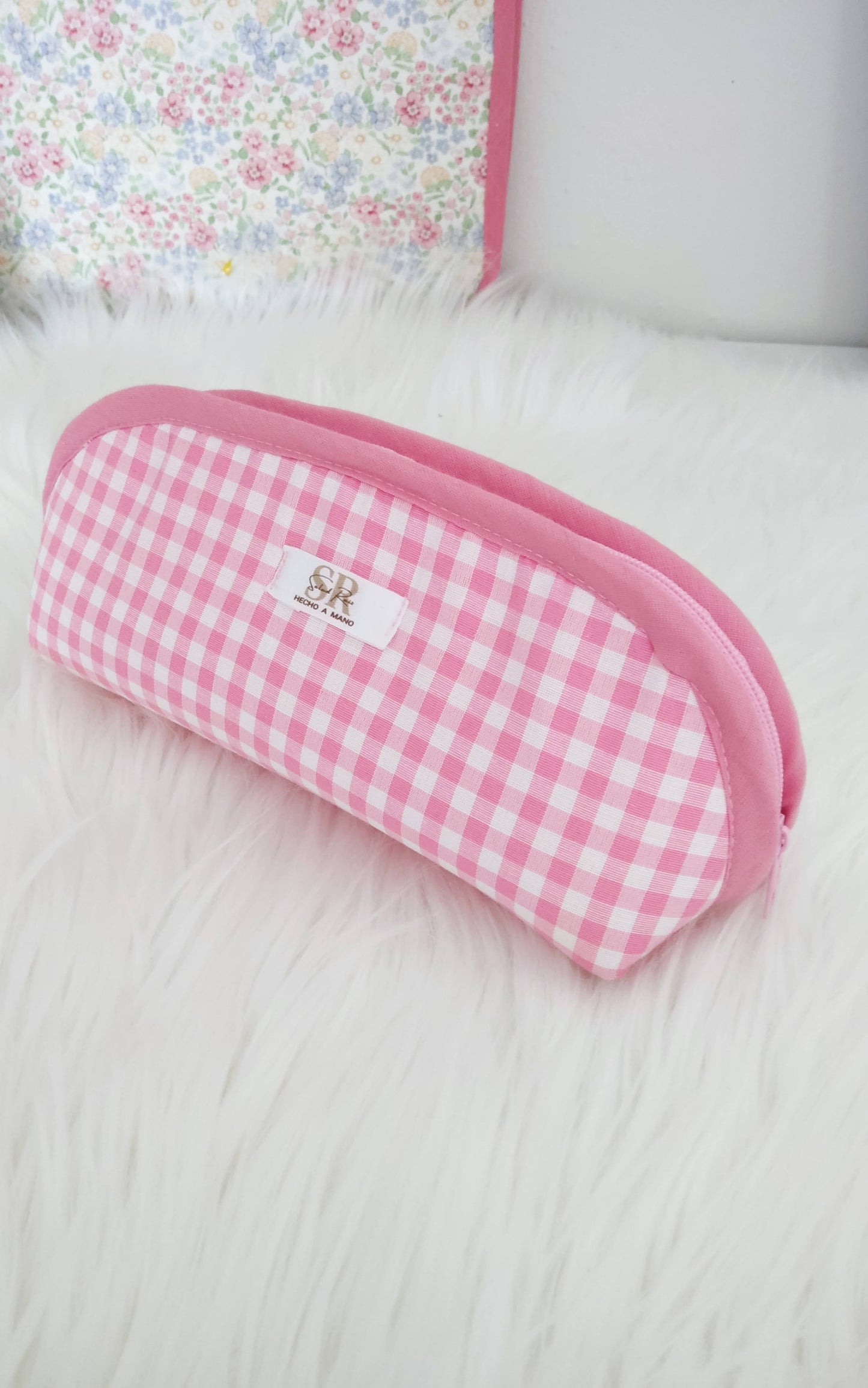Estuche de tela acolchado con estampado de cuadros Vichy rosa y blanco sobre fondo blanco.